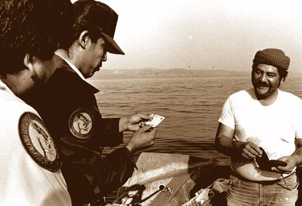 A tribal fisher is happy to show his license to tribal conservation officers.